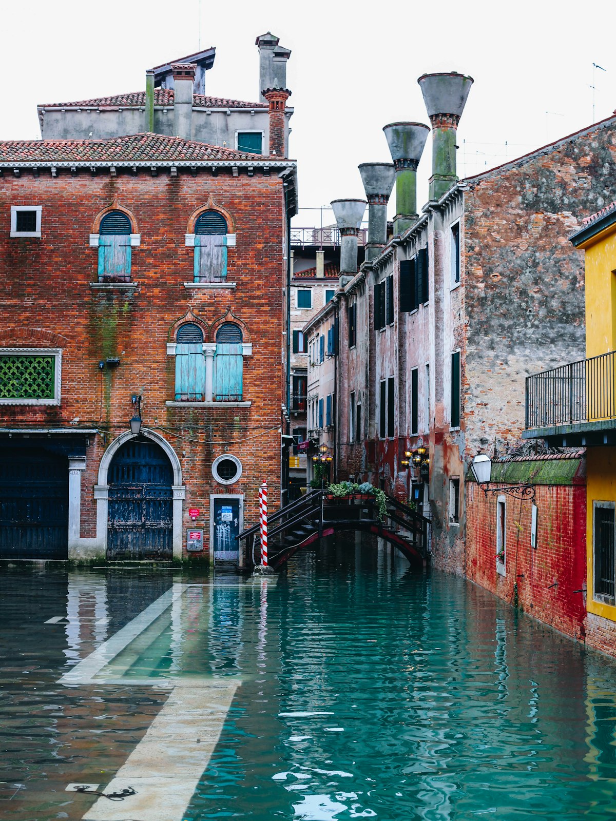 Piazza San Marco partially flooded during acqua alta with tourists wading through shallow water