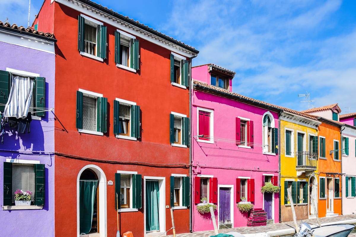 Colourful Burano canal with fishing boats moored alongside painted houses